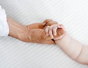 Adult hand holding infant's hand